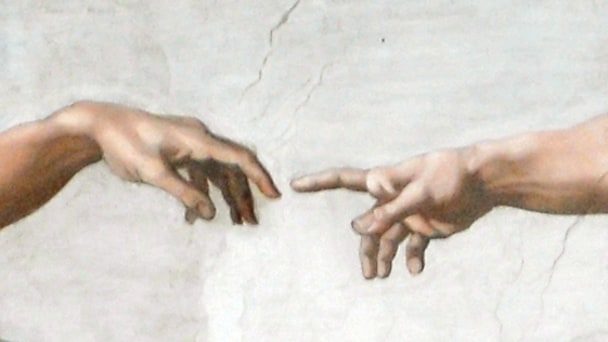 Zwei ausgestreckte Hände, deren Zeigefinger sich beinahe berühren.