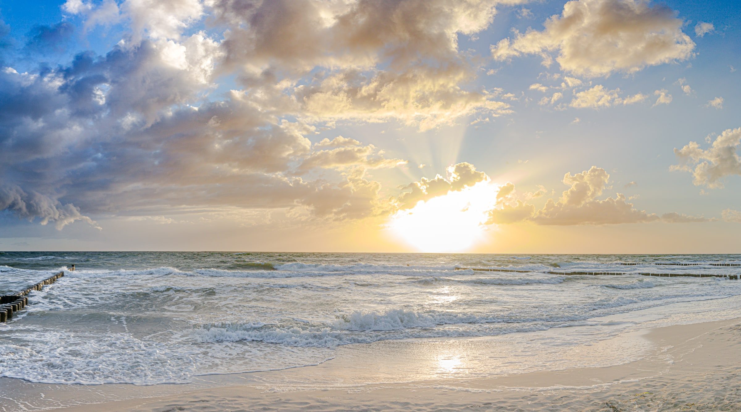 Meer und Strand im Abendlicht Sonnenuntergang über dem Meer, Wellen laufen auf einen Strand mit Buhnen